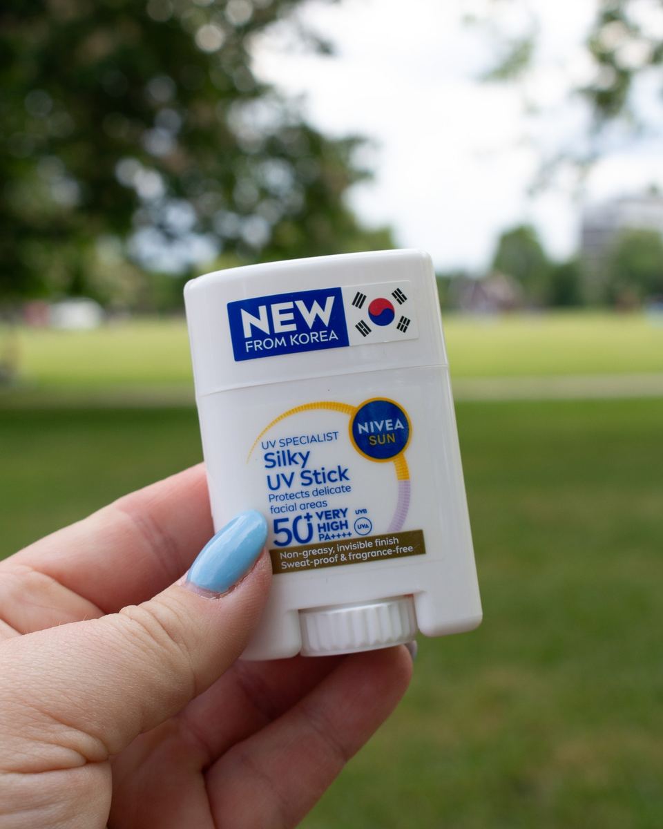 Hand holding a Nivea Silky UV Stick in a sunny park